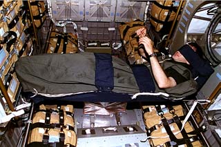 STS-81 mission specialist Jeff Wisoff is photographed in his sleeping bag (wearing a sleep mask) in the Spacehab module.